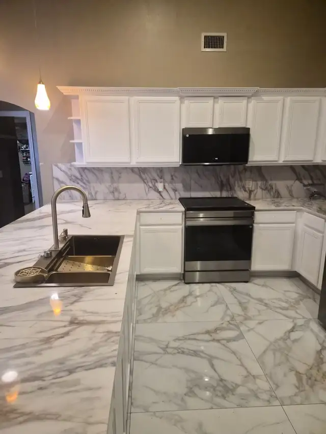 Kitchen with white shaker cabinets, marble-look countertops, a full-height marble-look backsplash and a stainless range